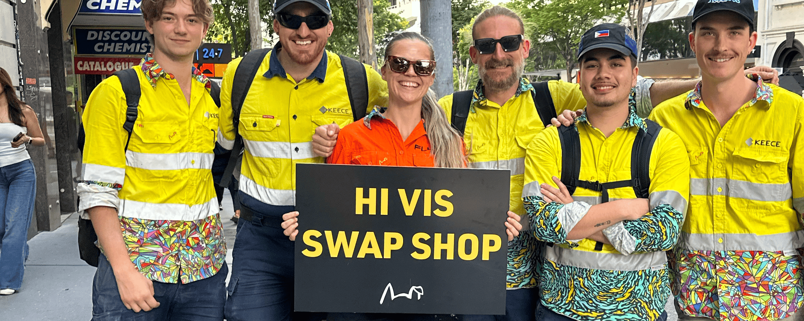 Group of people in high-visibility clothing holding a sign for a swap shop event.